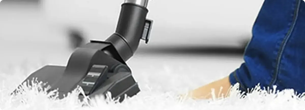 Close-up of a professional vacuuming a white carpet in Compton.